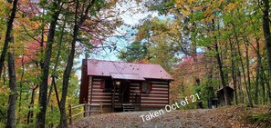A rustic cabin surrounded by autumn foliage.