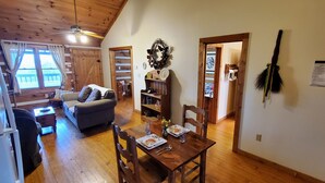 A cozy cabin interior with a dining area, a living room with a sofa, and a kitchen area.