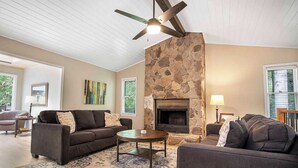 A living room with a stone fireplace, two sofas, a coffee table, and a ceiling fan.