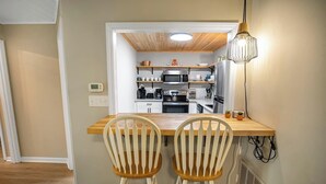 A compact kitchen with modern appliances, a wooden dining table, and two chairs.