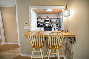 A compact kitchen with modern appliances, a wooden dining table, and two chairs.