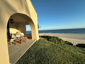 A beachside lounge with a view of the ocean, a small table, and a bench. - Luxury Beachfront Condo - Best Location in Casa Del Mar!  (San Jose del Cabo)