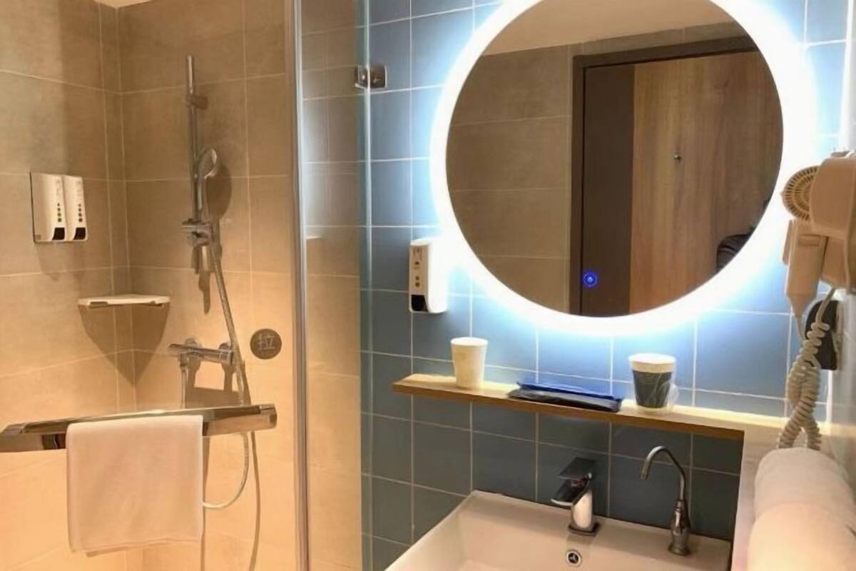 A bathroom with a shower, a sink, a mirror, and a towel rack.