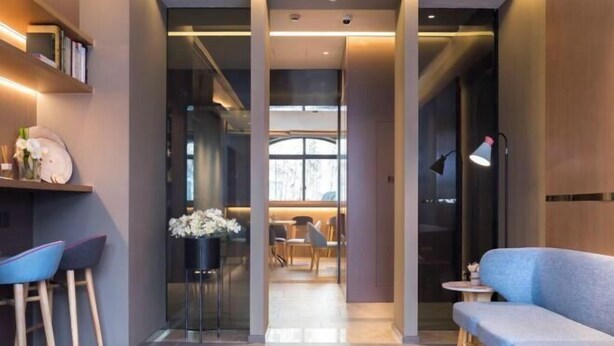 A modern interior with a sofa, chairs, a table, and a bookshelf. - Homeinn · neo (Zhaoqing Qixingyan Paifang) (Zhaoqing)