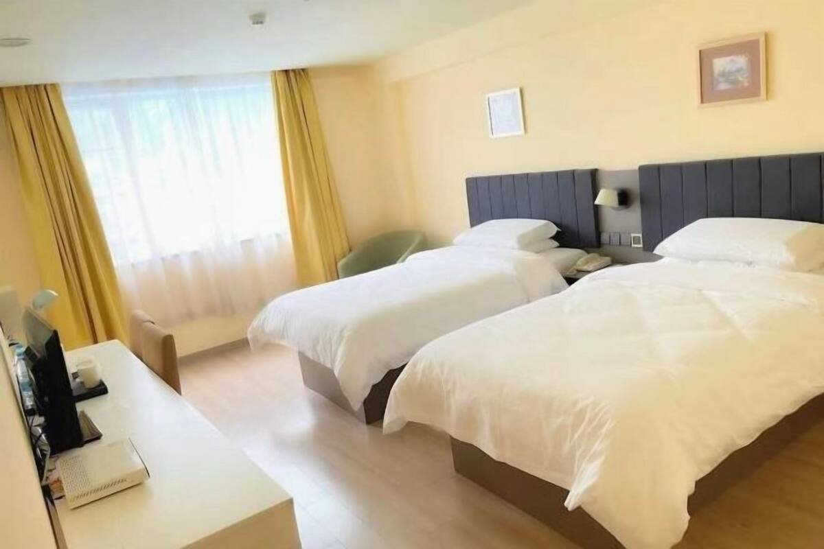 A hotel room with two beds, a desk, and a chair.