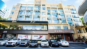 A multi-story hotel with a modern facade, featuring a prominent sign for 'Kingfu' and a 'homeinn' hotel. There are several cars parked in front, and the building has a flat roof with air conditioning units visible. - Homeinn · neo (Zhaoqing Qixingyan Paifang) (Zhaoqing)