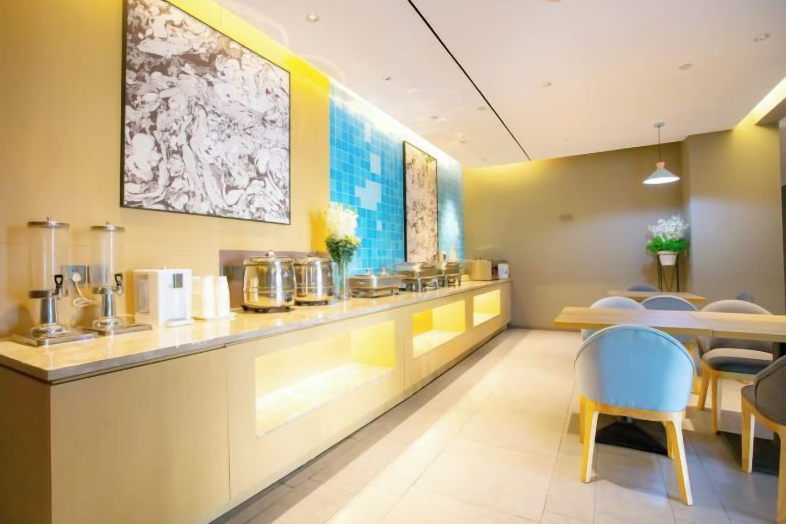 A modern hotel lobby with a long reception counter, seating area, and a dining space.