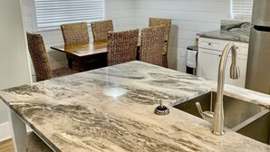 A kitchen with a marble countertop, stainless steel sink, wicker chairs, and pendant lighting. - 🏖30A Bridge to Paradise Bungalow 146: 2Bed/2Bath, 400 yds to Beach🏖 (Santa Rosa Beach)