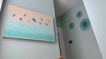A hallway with a wall-mounted artwork depicting a beach scene, a door, and decorative wall plates.