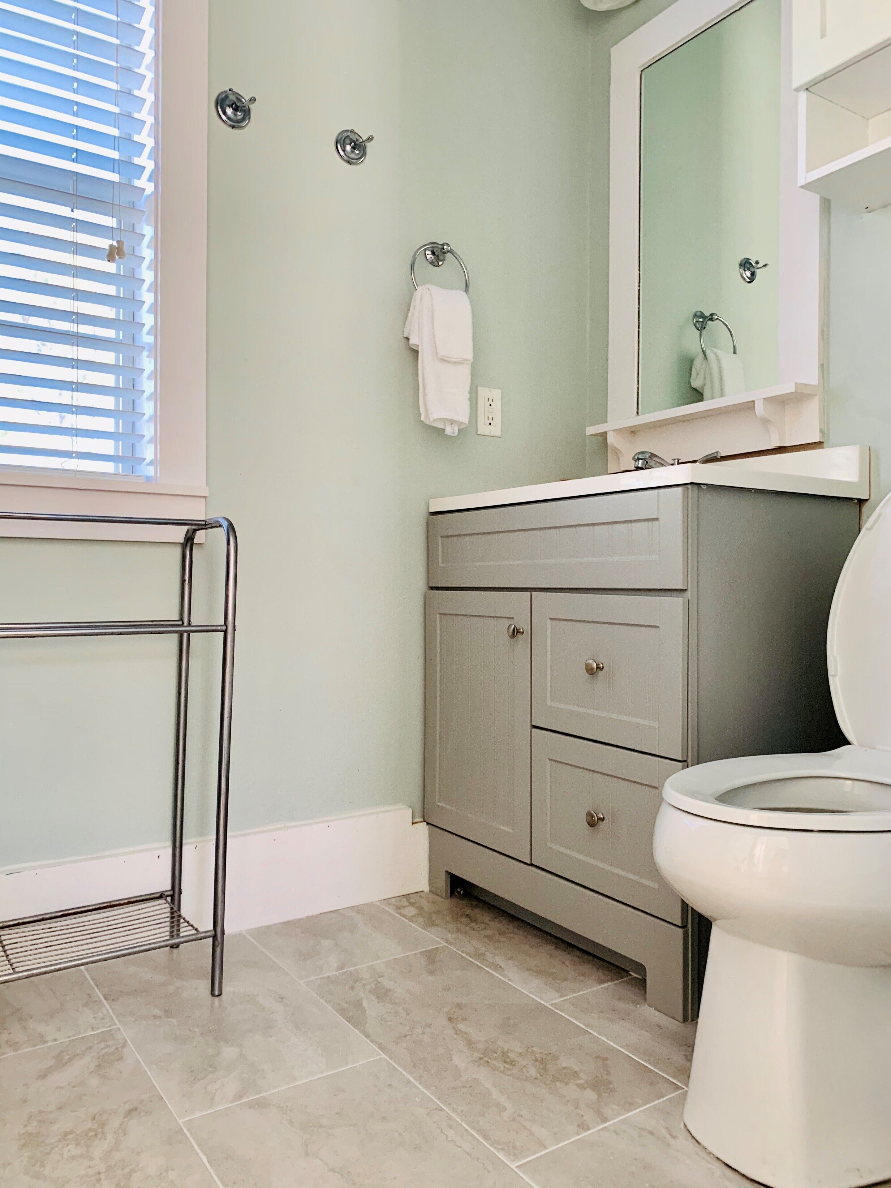 Une salle de bain comprenant des toilettes, un meuble-lavabo avec un miroir et un porte-serviettes.