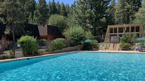 A clear swimming pool surrounded by trees and buildings. - Peaceful Creekside Retreat with Pool Access, Family-Friendly (Incline Village)