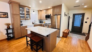 A modern kitchen with wooden cabinets, a stainless steel refrigerator, and a granite countertop. - Peaceful Creekside Retreat with Pool Access, Family-Friendly (Incline Village)
