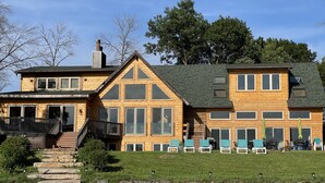 A large wooden house with a stone staircase, multiple windows, and outdoor seating area. - Log Cabin w/indoor pool on Lake, 30 Min from Wis Dells! 8 min. from Sand Valley (Arkdale)