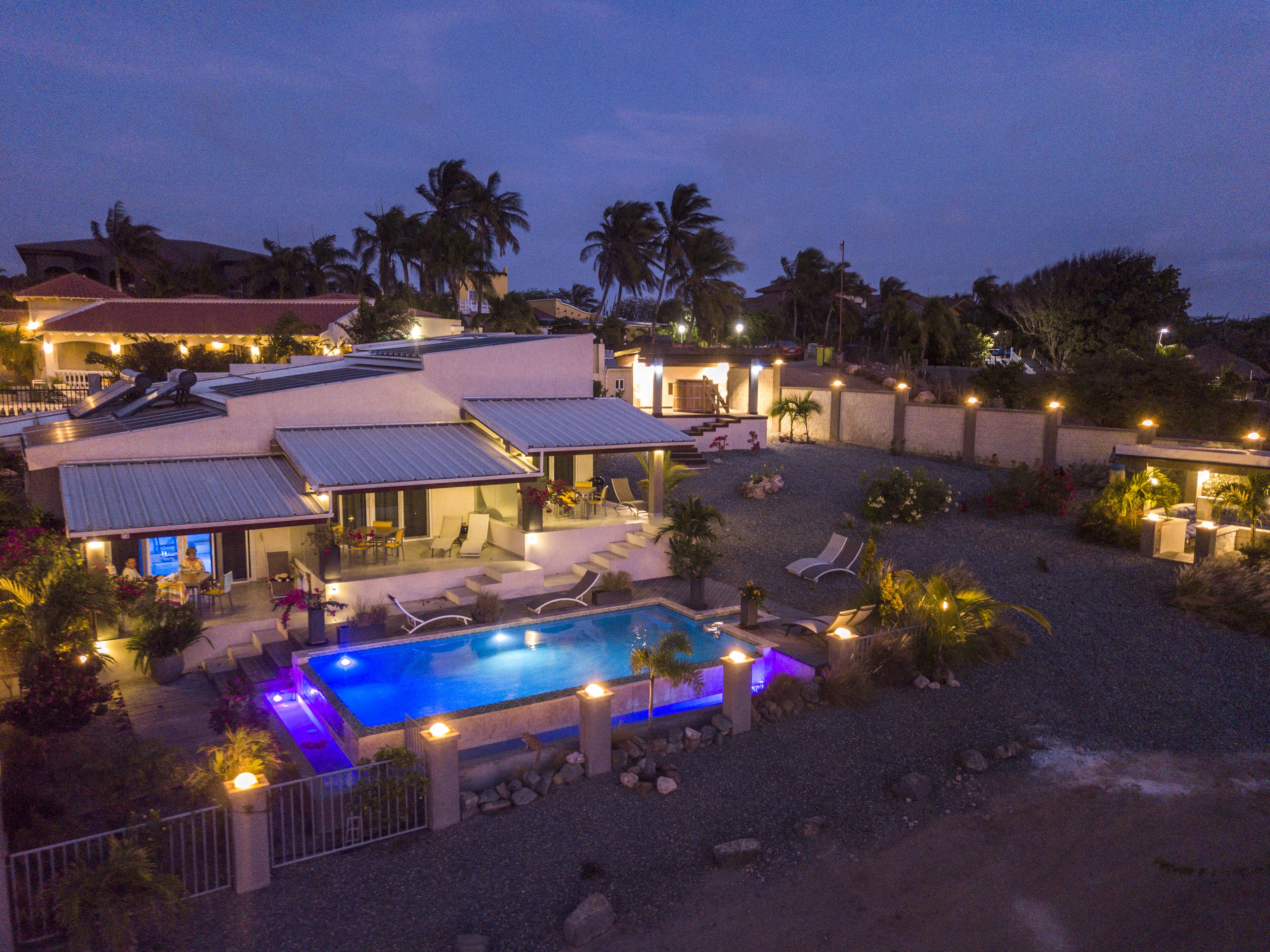 A residential area with a swimming pool, multiple houses, and a well-lit patio area.