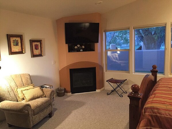 A cozy living room with a fireplace, a television mounted above it, and a comfortable armchair. - Moab Rim Village Oasis (Moab)