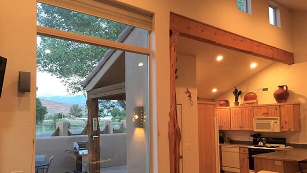 A compact kitchen with wooden cabinets, a microwave, and a dining area with a table and chairs. - Moab Rim Village Oasis (Moab)