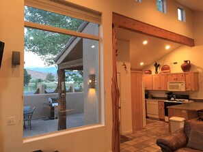 A compact kitchen with wooden cabinets, a microwave, and a dining area with a table and chairs. - Moab Rim Village Oasis (Moab)