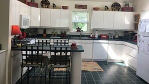 Een keuken met witte kasten, een zwart aanrecht en een eethoek met twee stoelen.