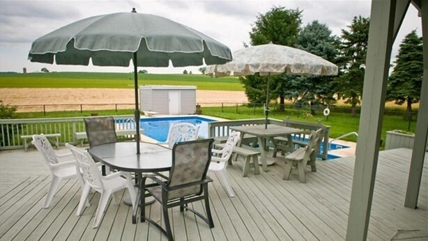 Een overdekt terras buiten met een pooltafel, stoelen en parasols.
