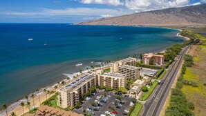 Un hotel frente al mar con varias edificaciones, un estacionamiento y una carretera a lo largo de la playa.