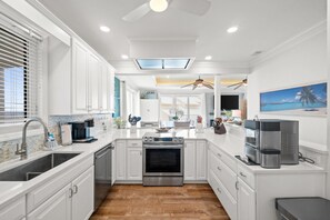 A modern kitchen with white cabinetry, a stainless steel oven, and a coffee maker.