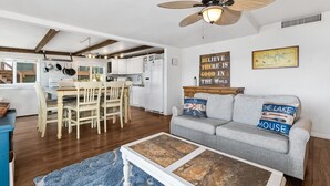 A spacious living area with a dining table, a sofa, and a ceiling fan.