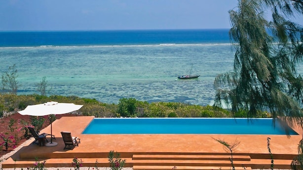 A pool with a view of the ocean and a boat in the distance. - Villa Paradise ON THE Ocean (Matemwe)