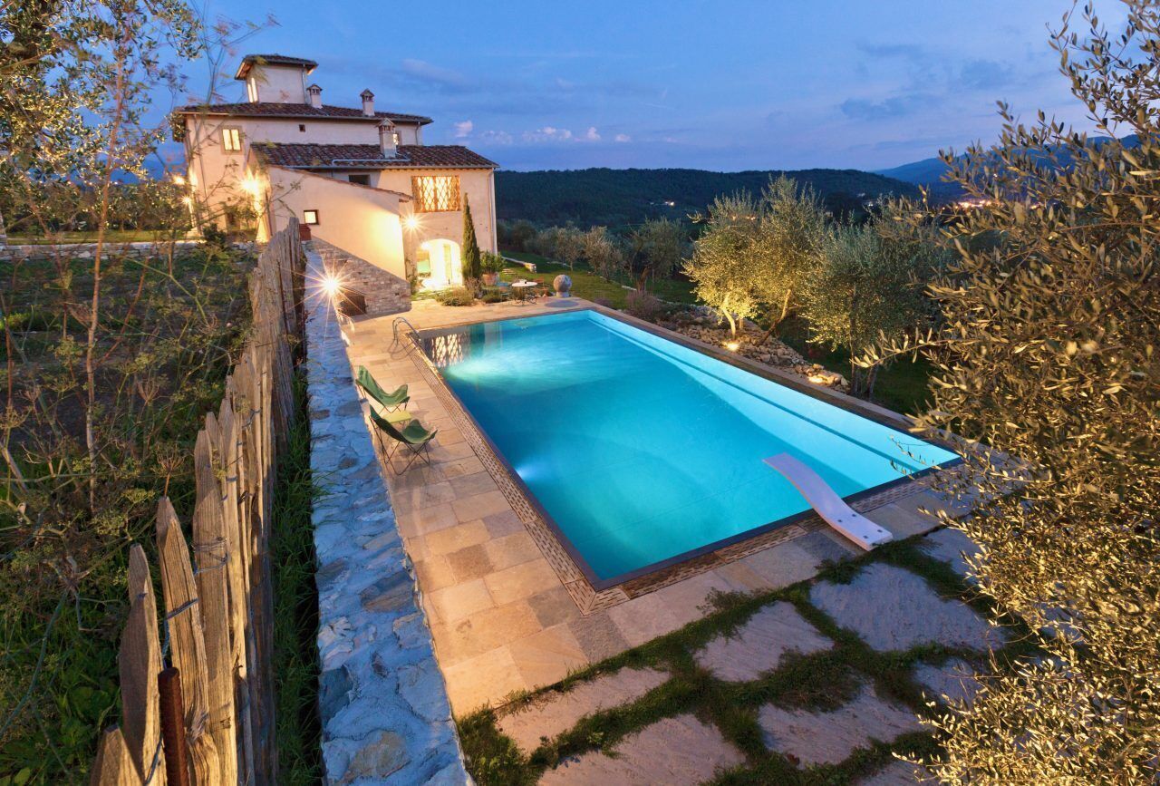 A rectangular pool with a stone border, surrounded by a stone pathway and a wooden fence.