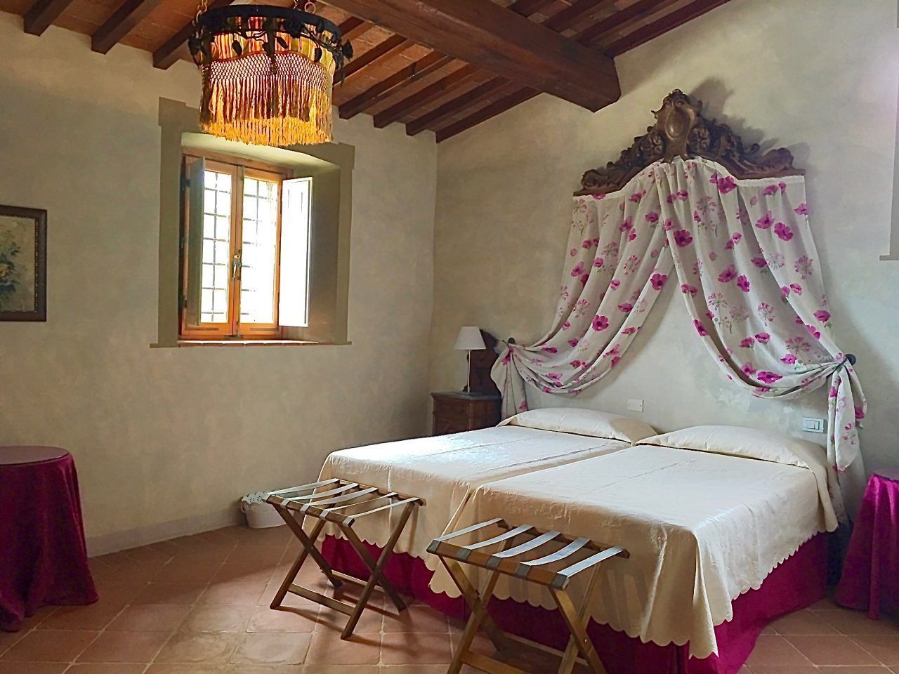 A bedroom with a bed, a window, a hanging light fixture, and a chair.