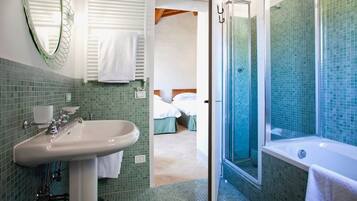Un baño con lavamanos, espejo y zona de ducha.