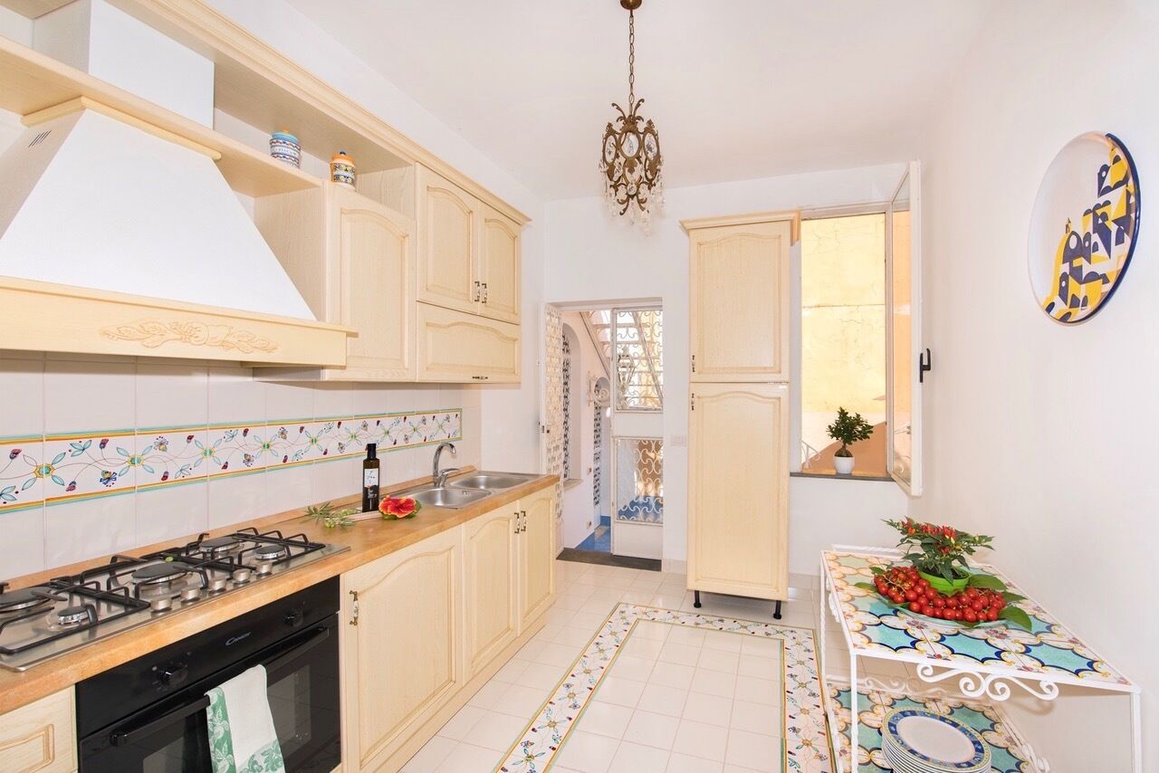 A kitchen with light wooden cabinets, a gas stove, and a tiled backsplash.