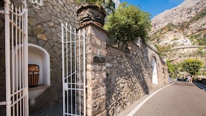 Un edificio de piedra con una verja blanca, una ventana pequeña con un jarrón, y un letrero que dice "130".