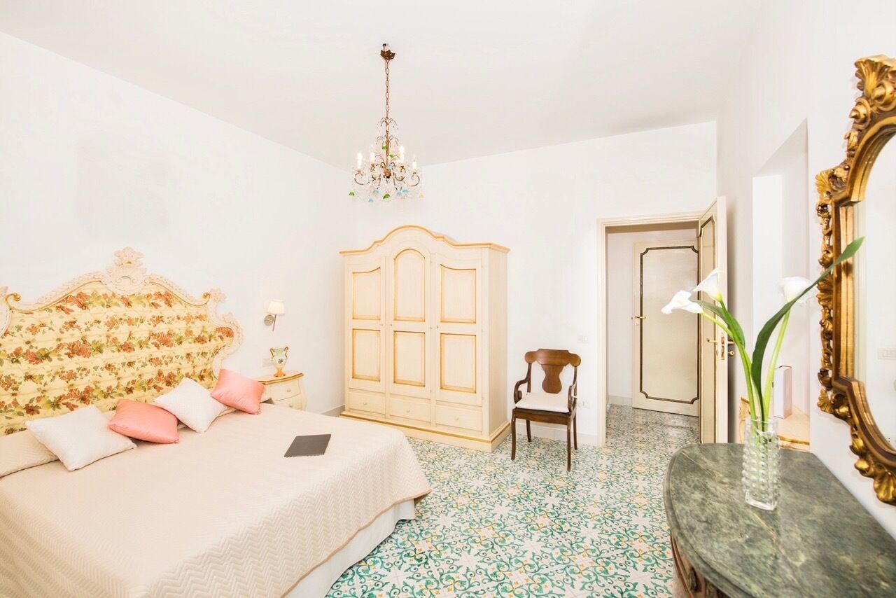 Une chambre à coucher avec un lit, une armoire en bois, une chaise, un miroir et un lustre.