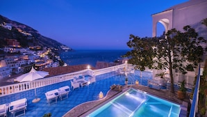 Una piscina en la azotea con vistas al mar y a un pueblo.