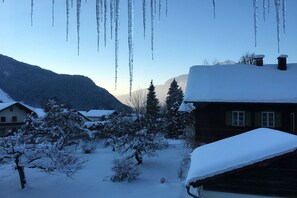Un paisaje cubierto de nieve con casas y cascabeles de hielo colgando del techo.