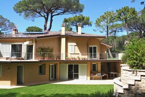 A two-story house with a balcony, a stone retaining wall, and a well-maintained lawn. - Villa Stella Marina (Castiglione della Pescaia)