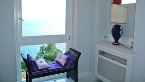 A room with a view of the sea, a bench with cushions, a lamp, and a white console table. - Villa Luce (Praiano)