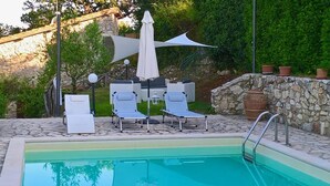 Uma área de piscina com espreguiçadeiras e um guarda-sol.