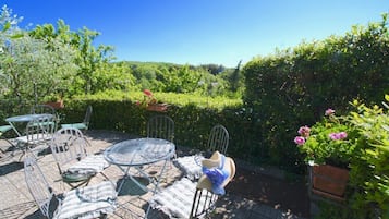Relax in style with a patio offering a serene view of lush green surroundings, perfect for dining or unwinding.