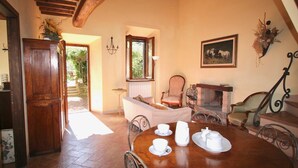 Uma área de refeições com uma mesa de madeira posta para o chá, uma lareira e vista para o exterior.
