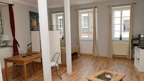 A room with a wooden table, a chair, a glass-top coffee table, and a window with curtains. - Haus Weihertor (Traben-Trarbach)