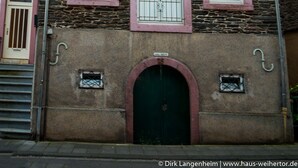 A stone building with pink-framed windows and a green door. - Haus Weihertor (Traben-Trarbach)
