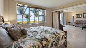 A bedroom with a large bed, a view of the beach, and a living area with a sofa and lamp. - Spectacular Oceanfront Views in Miami's Safest Beachfront Community  (Surfside)