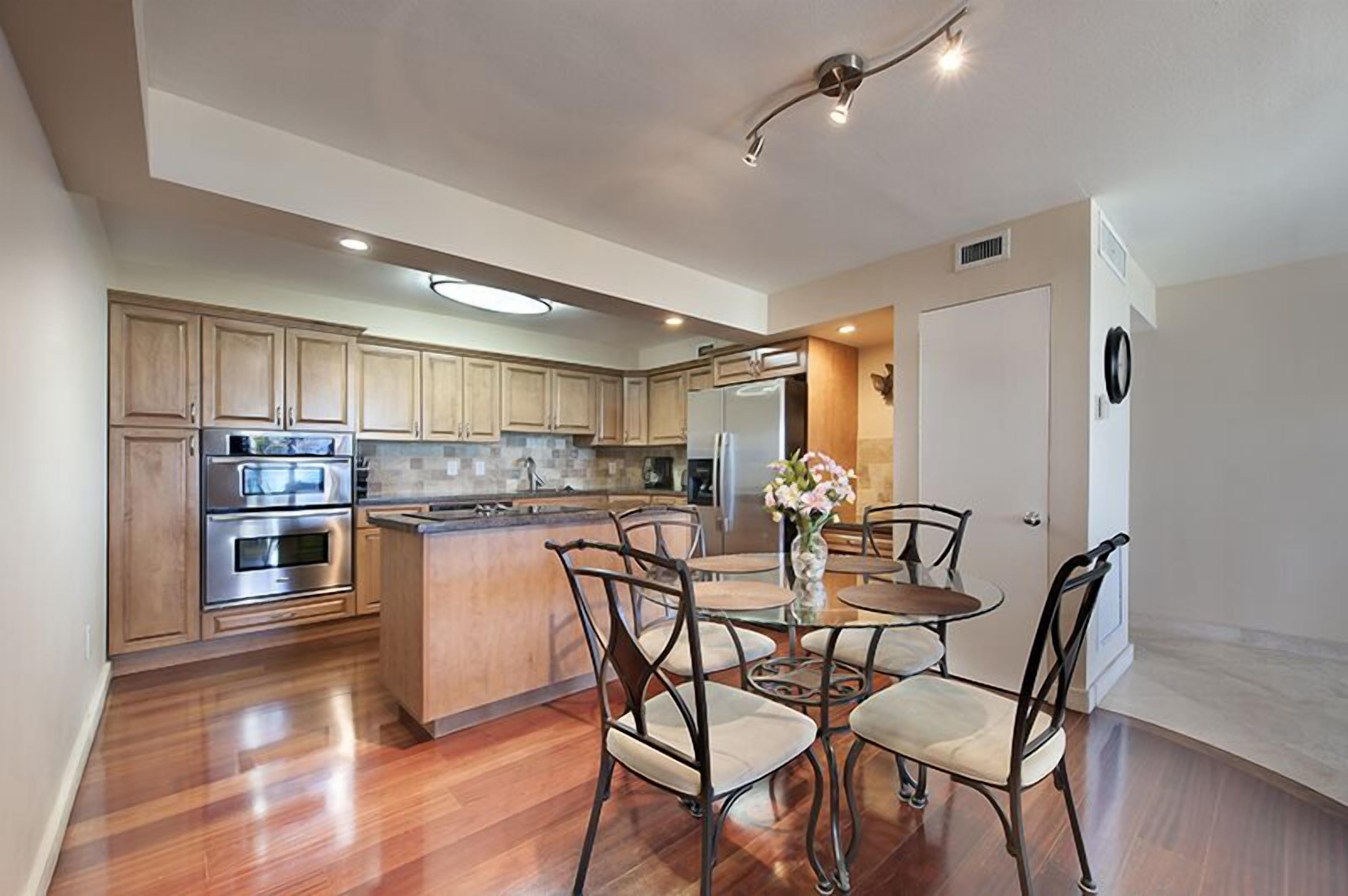 A modern kitchen with wooden cabinets, stainless steel appliances, and a central island with seating.