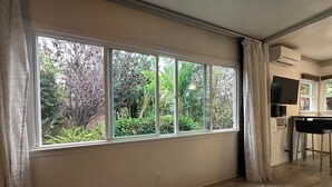 A room with a large window, a TV mounted on the wall, and a bar area.