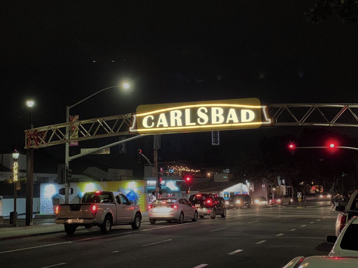 A street sign with the name 'CARLSBAD' at night.