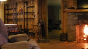 A cozy living room with a fireplace, wooden bookshelves, and a large window overlooking a scenic view. - Mountain Rustic Ski House Tahoe-Reno  Mt Rose-Snow Resort 1.5 Miles (Reno)