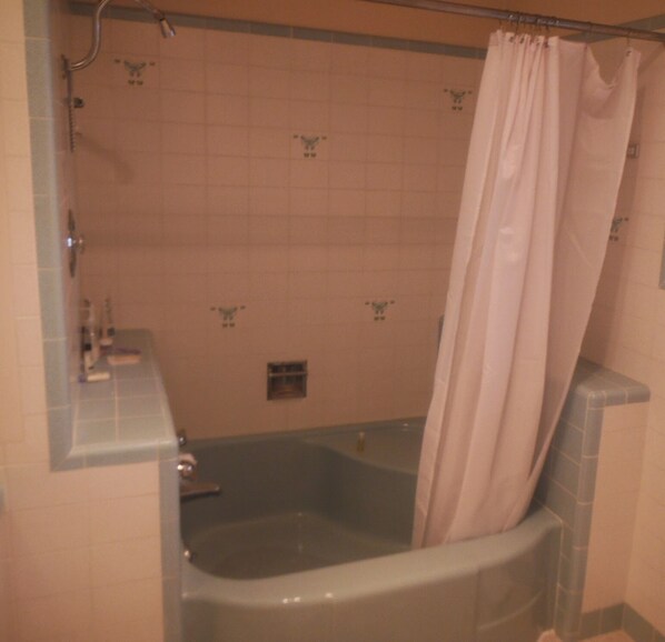 Un baño con bañera, cortina de ducha y paredes de azulejos.