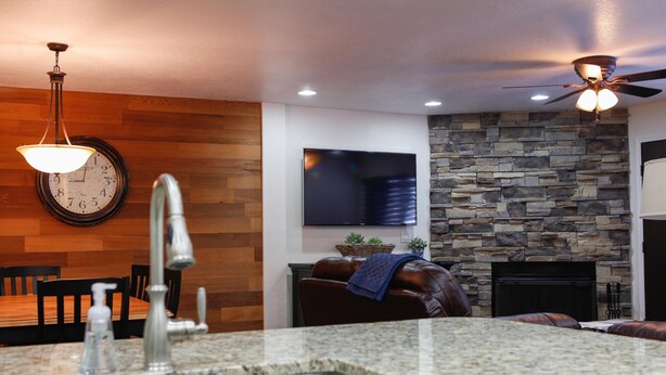 A modern kitchen with granite countertops, a built-in sink, and a stone wall.