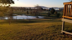 A grassy area with a wooden deck, a pond, and distant mountains. - Mt Baker, San Juans, WWU, Sea to Ski race,  Canada, Golf, Refineries, 2 Bd/2 bth (Ferndale)